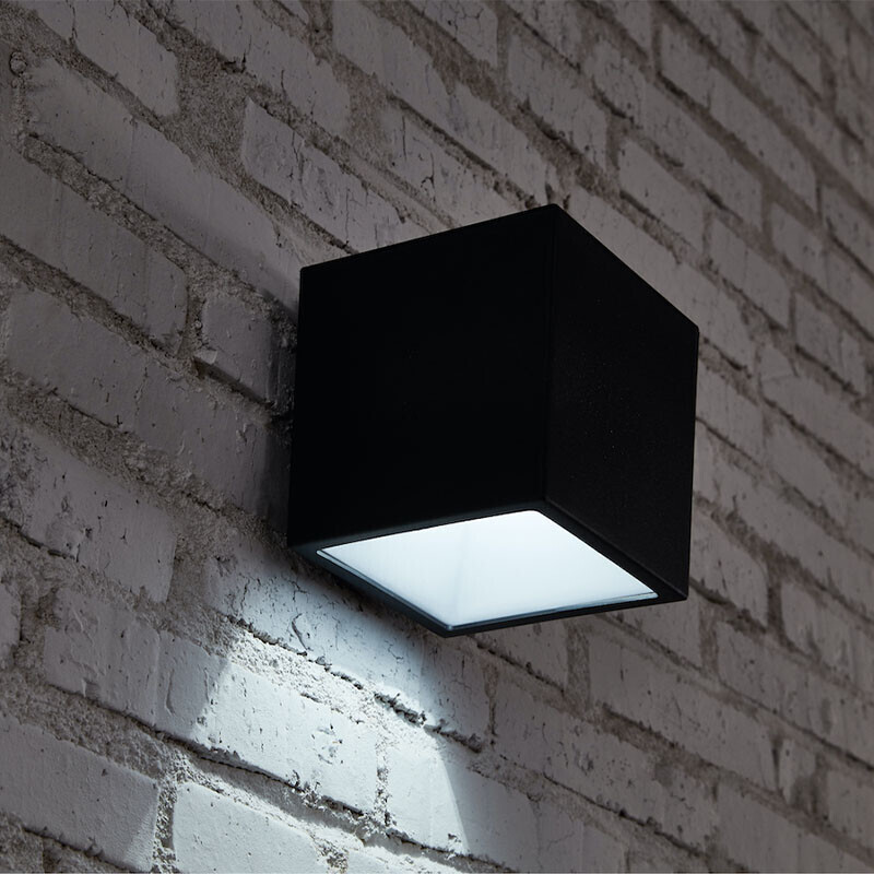 Kubus wandlamp op zonne-energie gemonteerd en brandend in het donker
