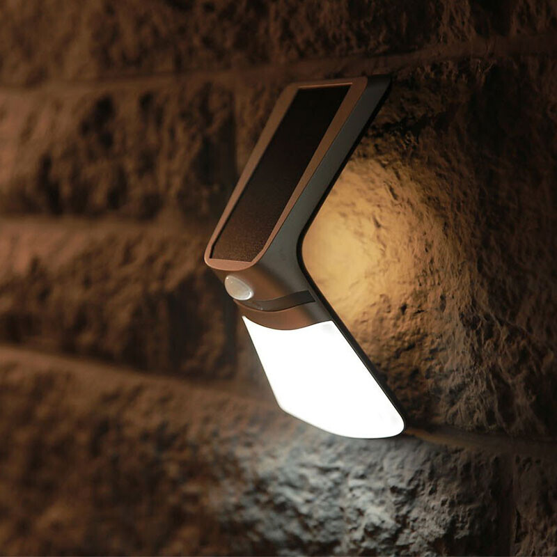 Solar wandlamp brandend op muur in het donker met warm licht