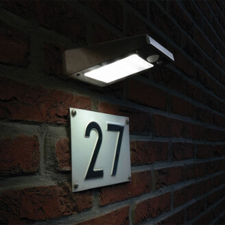 Solar wandlamp verlicht huisnummer op bakstenen muur in het donker