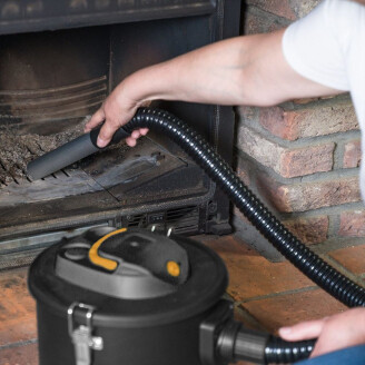 Man gebruikt 800W aszuiger om as uit een houtskoolbarbecue te verwijderen in de tuin.